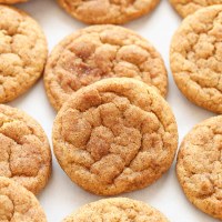 Several pumpkin cookies lined up on a piece of parchment paper.