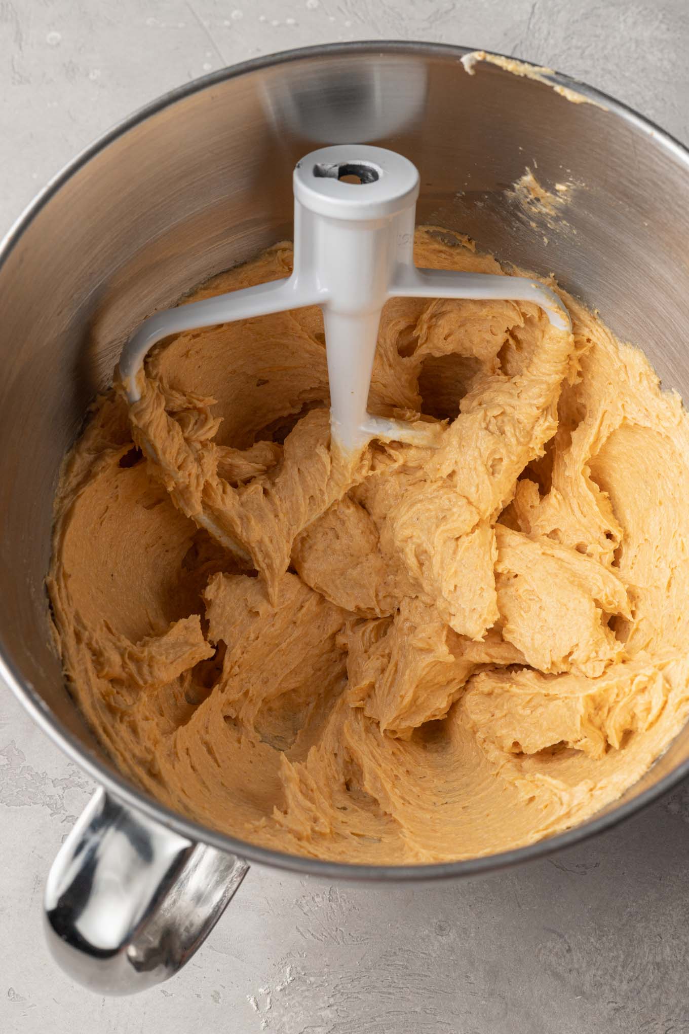 An overhead view of the wet ingredients for pumpkin sugar cookies in a stand mixer. 