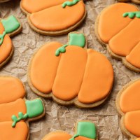 Several iced pumpkin sugar cookies on a piece of parchment paper.