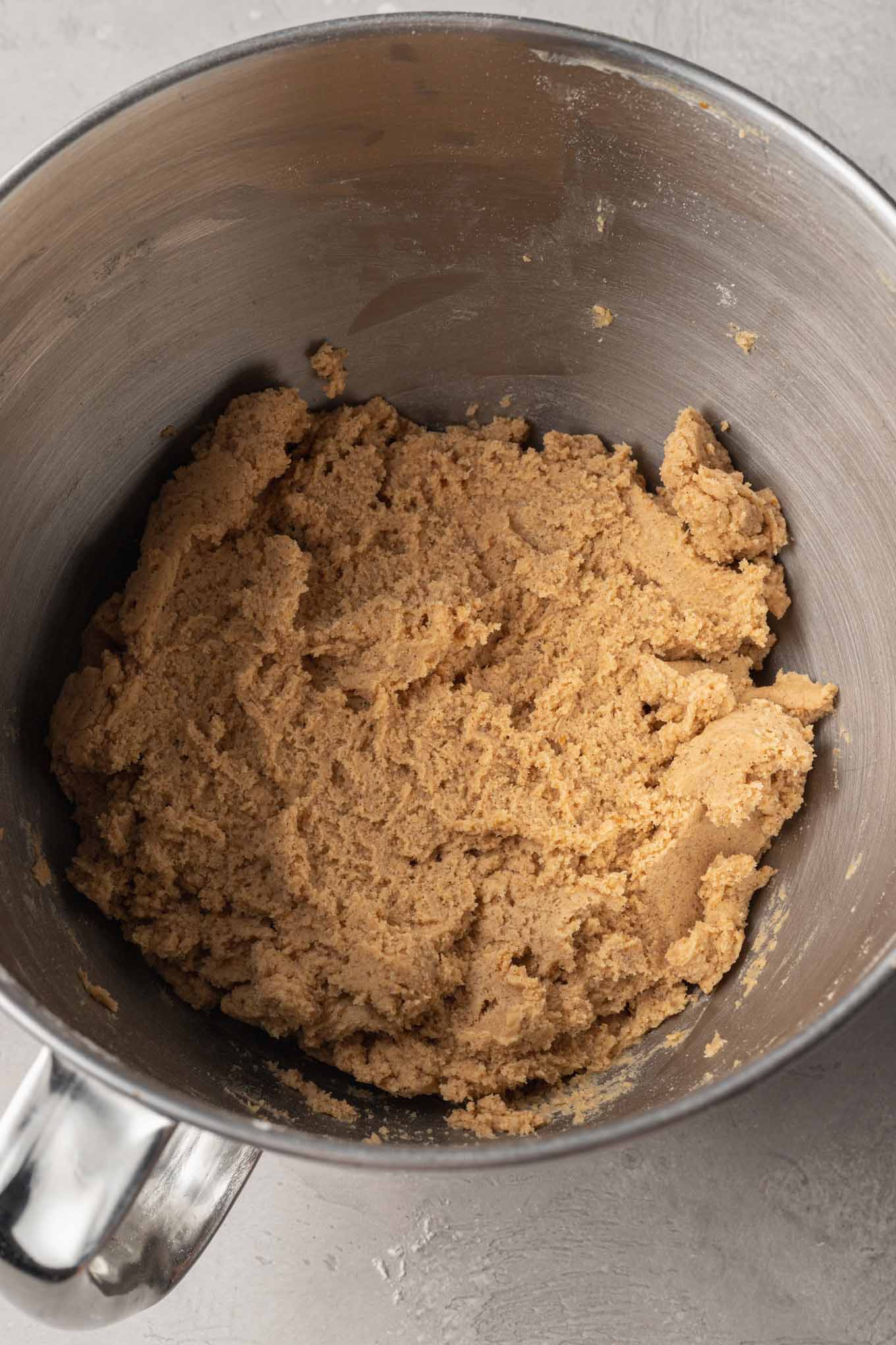 An overhead view of pumpkin sugar cookie dough in the bowl of a stand mixer.