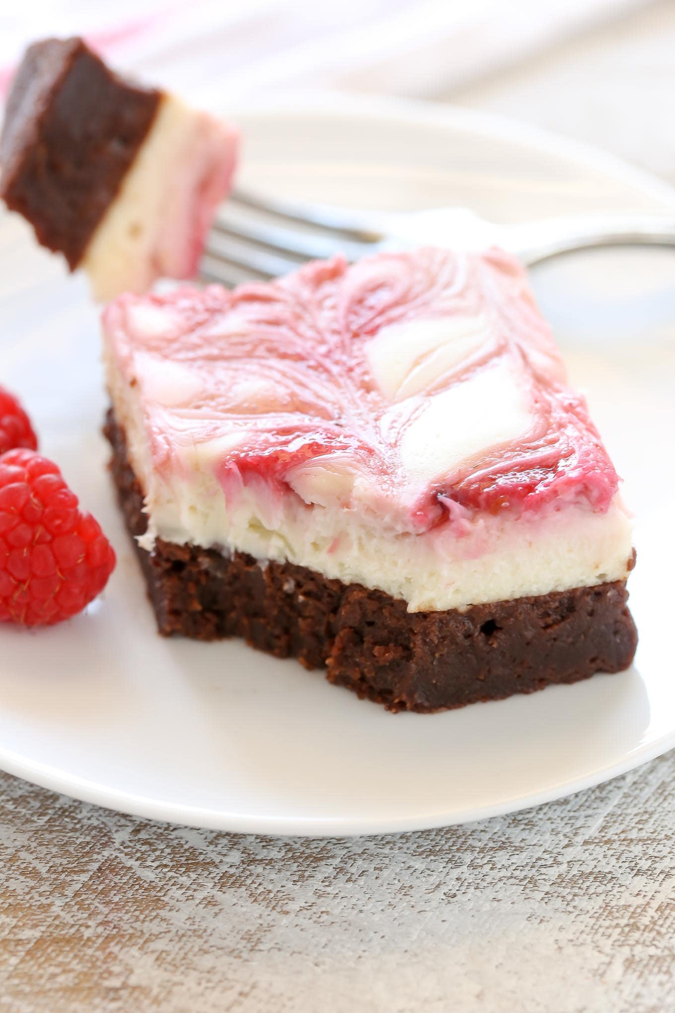 A fudgy brownie base topped with a smooth and creamy cheesecake layer and a raspberry swirl. These Raspberry Cheesecake Brownies make a beautiful dessert for any occasion!