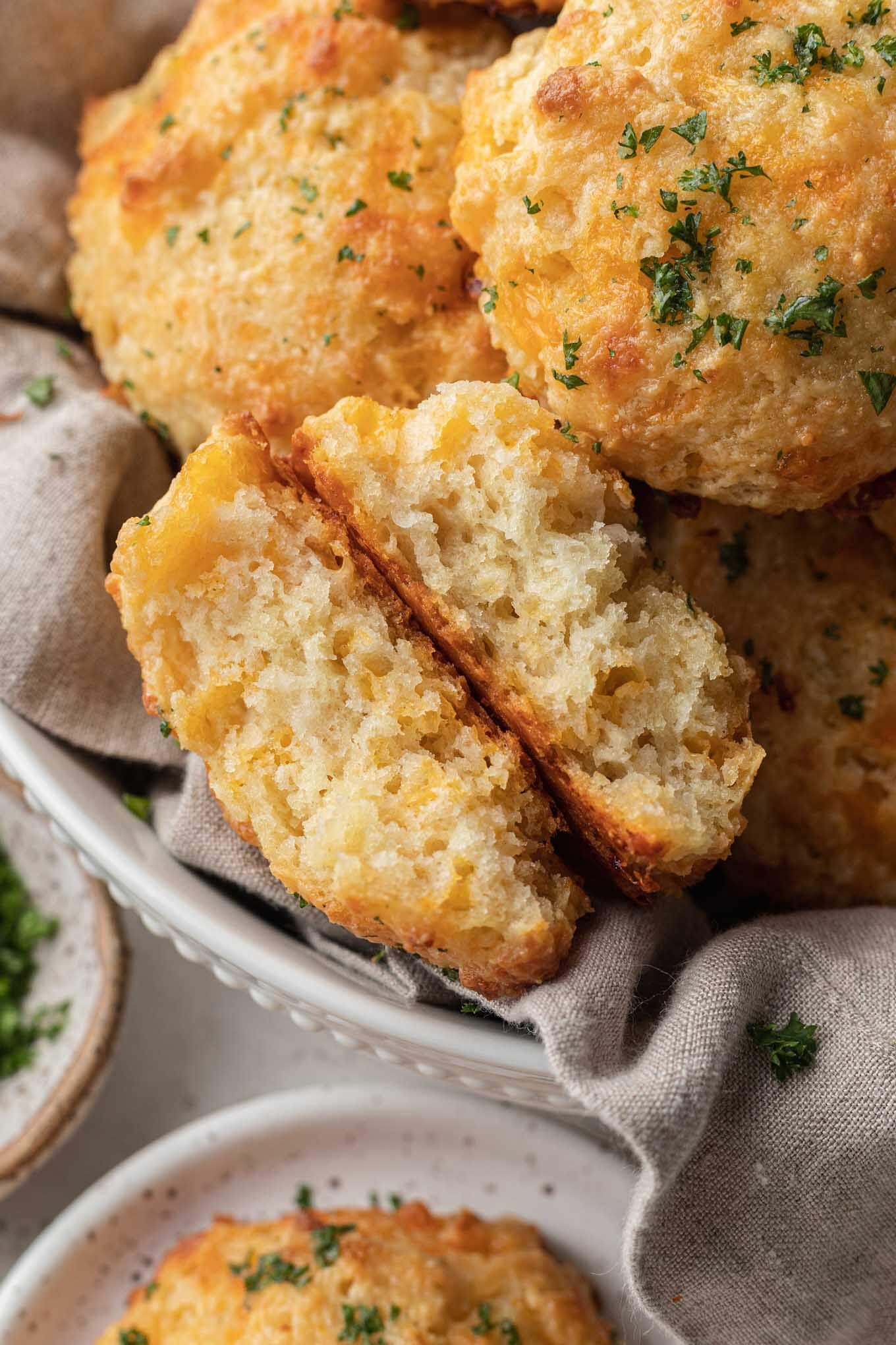 A halved Cheddar Bay Biscuit turned on its side in a basket of biscuits. 