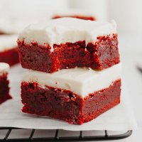 Two red velvet brownies stacked on top of each other. The top brownie has a bite missing.