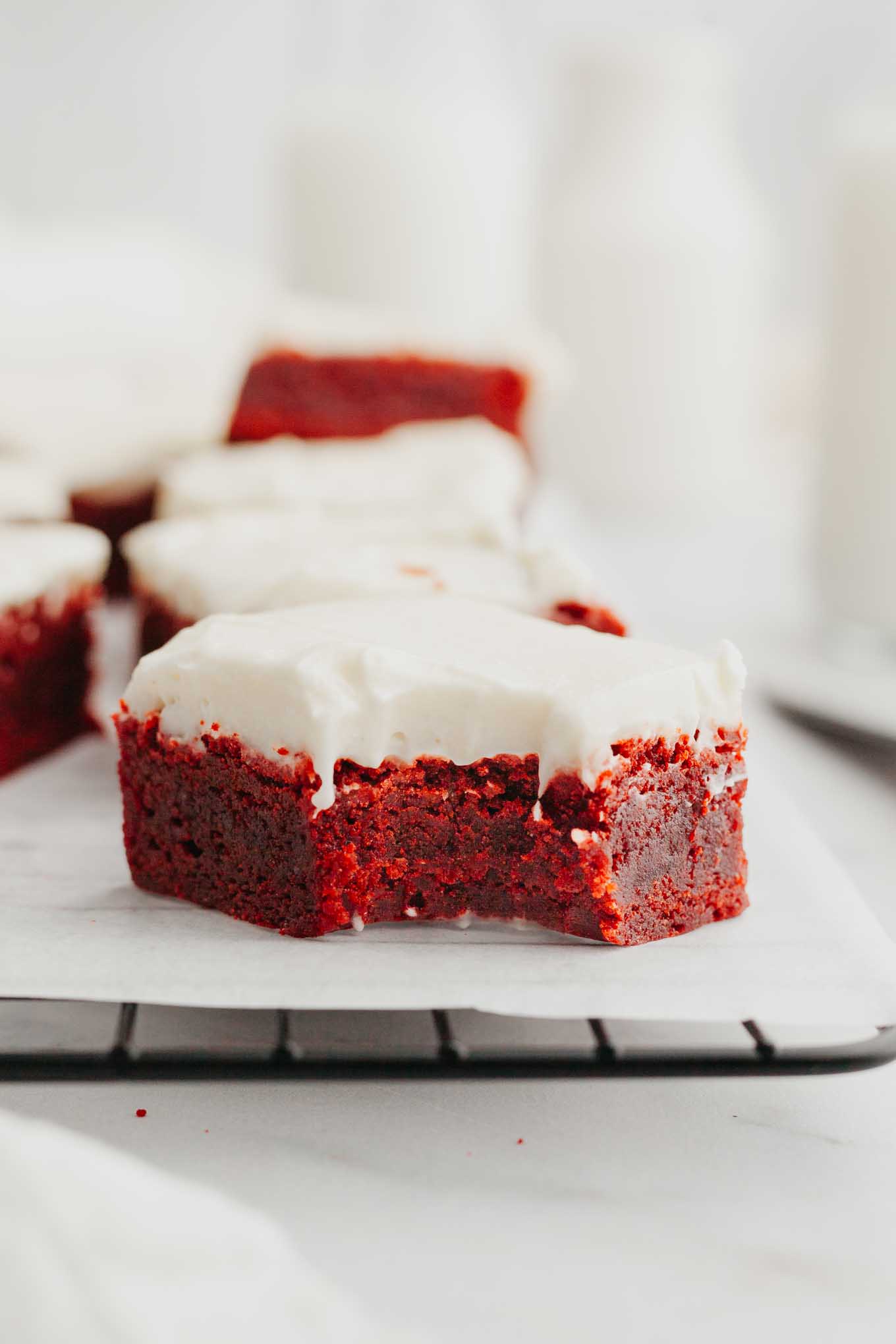 A side view of a red velvet brownie with a bite missing. 