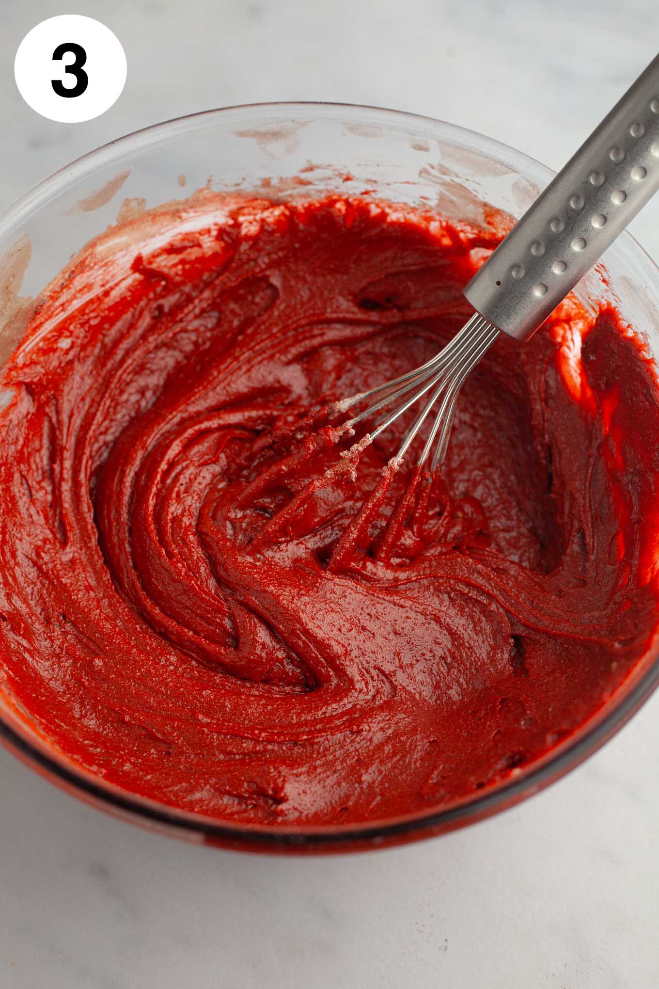 Red velvet brownie batter in a glass mixing bowl.