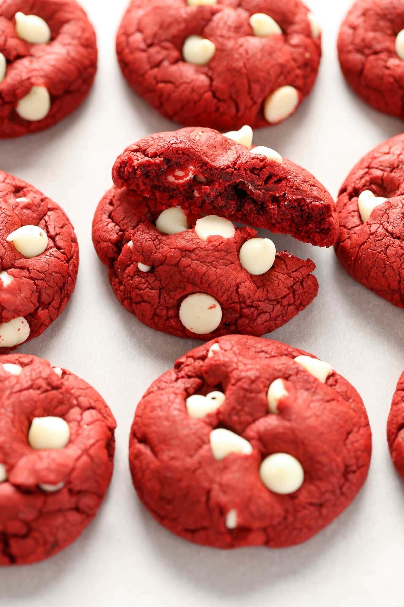 Three rows of red velvet cake mix cookies. The middle cookie has been broken in half. 