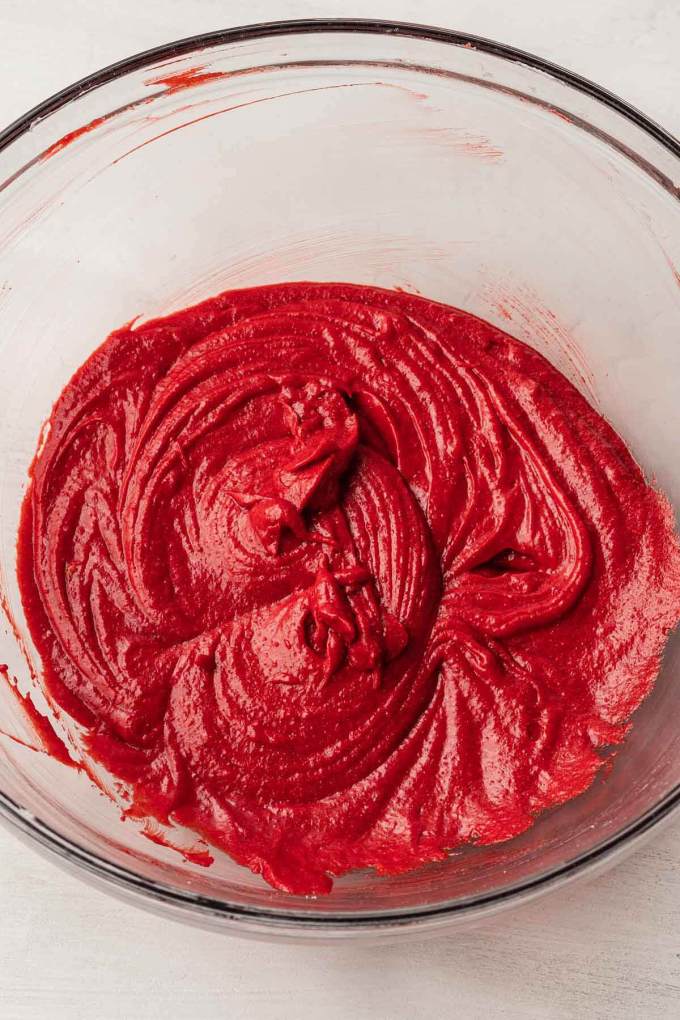 An overhead view of the wet ingredients for red velvet cookies in a glass mixing bowl.