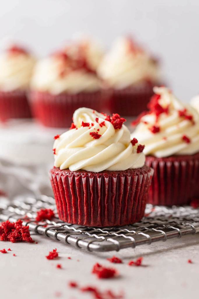 A side view of frosted red velvet cupcakes on a wire cooling rack. 