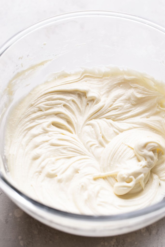 Cream cheese frosting in a glass mixing bowl. 