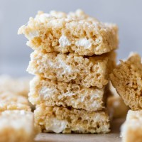 A stack of Rice Krispie treats on top of a wooden tray.