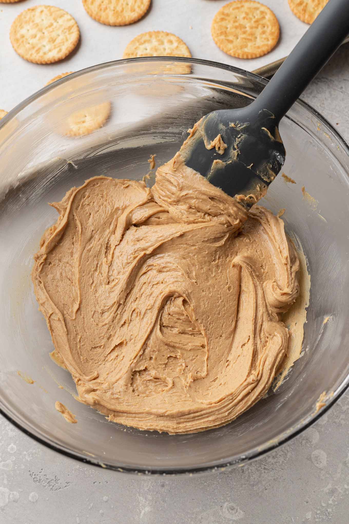 An overhead view of the peanut butter and powdered sugar mixed together in a glass mixing bowl.