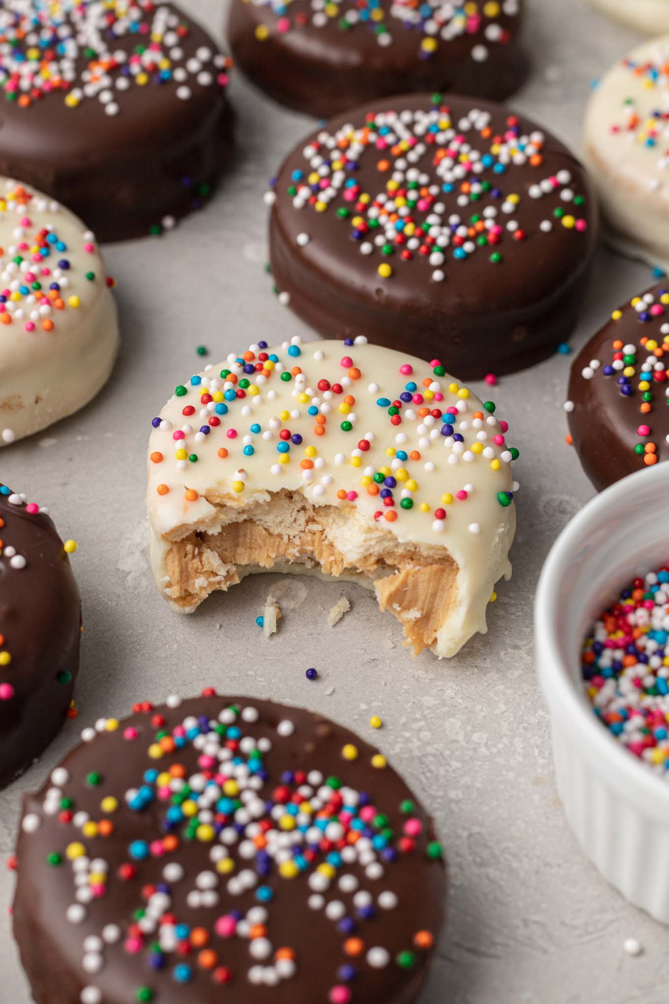 A white chocolate-coated Ritz cracker cookie with a bite missing. The cookie is surrounded by even more cookies. 