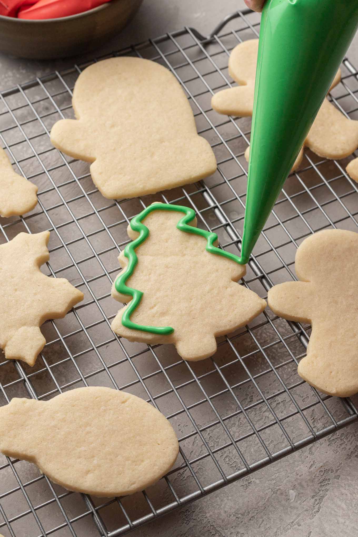 A tree shaped sugar cookie being outlined with green royal icing.