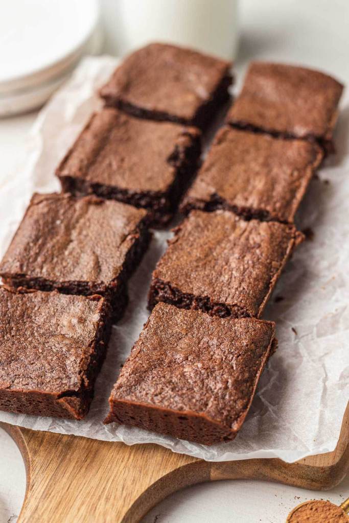 Eight brownie slices on a parchment-lined wood serving board. 