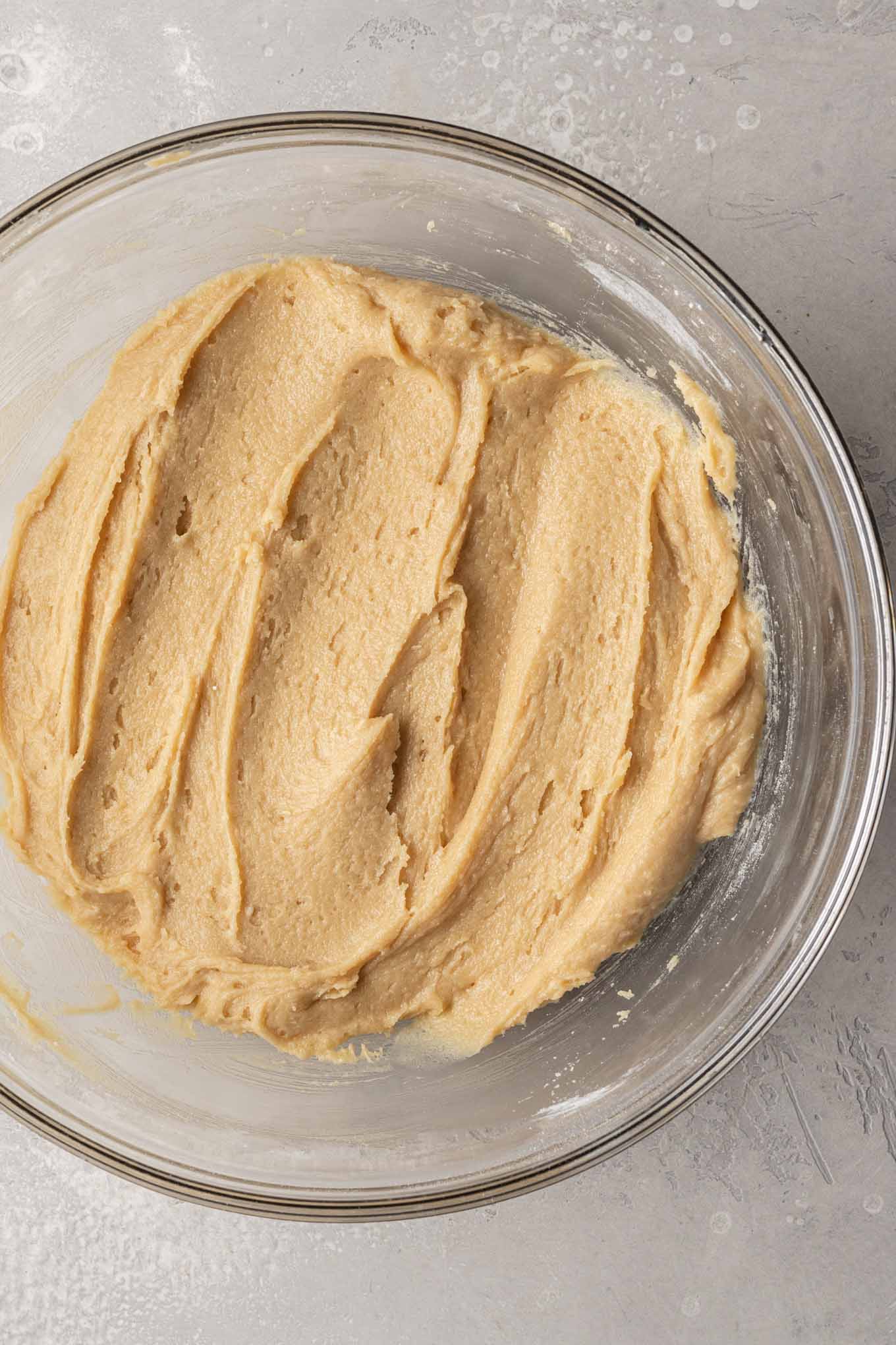 An overhead view of snickerdoodle cookie dough in a glass mixing bowl. 