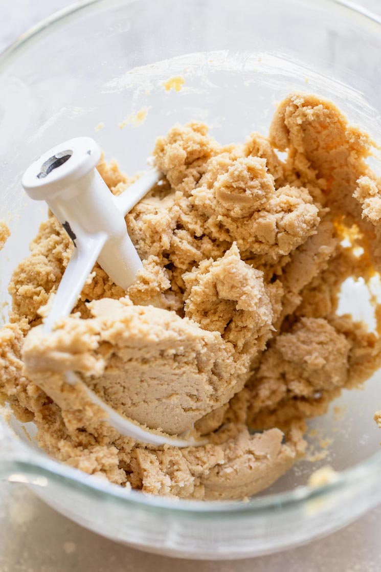 A glass mixing bowl filled with cookie dough that has been mixed up.