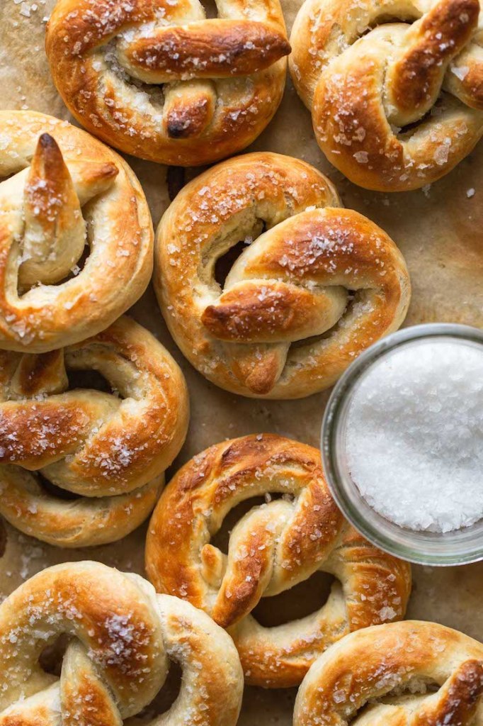 Overhead view of soft baked pretzels next to a dish of salt. 