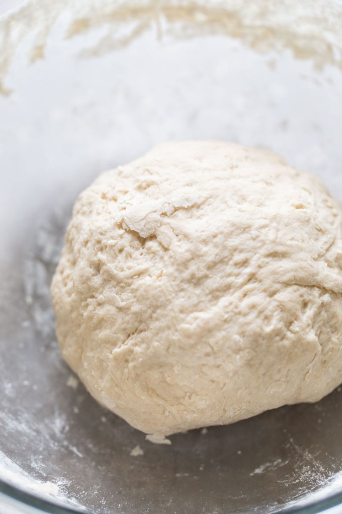 A ball of pretzel dough in a glass mixing bowl.