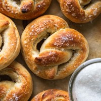 Overhead view of soft baked pretzels next to a dish of salt.