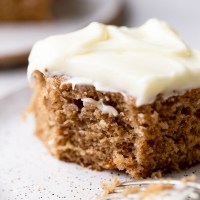 A single piece of spice cake on a speckled plate with a bite taken out of it.