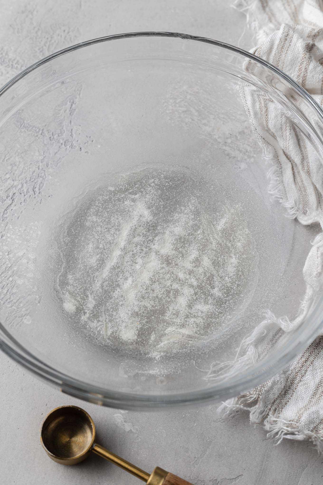 An overhead view of water and unflavored gelatin in a mixing bowl. 