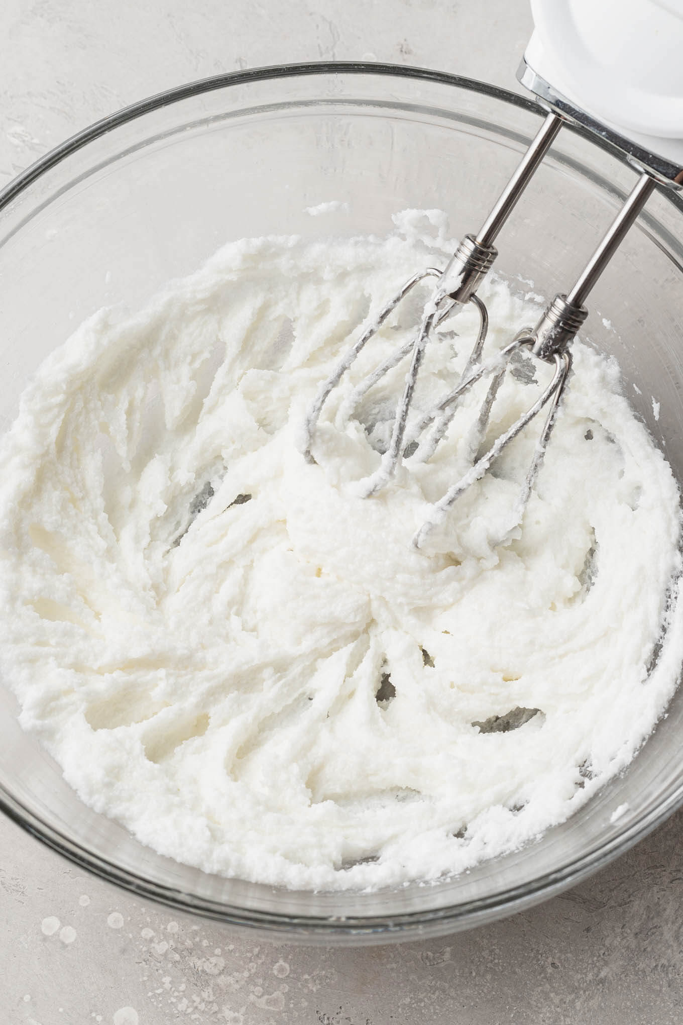 An overhead view of shortening and sugar being creamed together in a glass mixing bowl. 