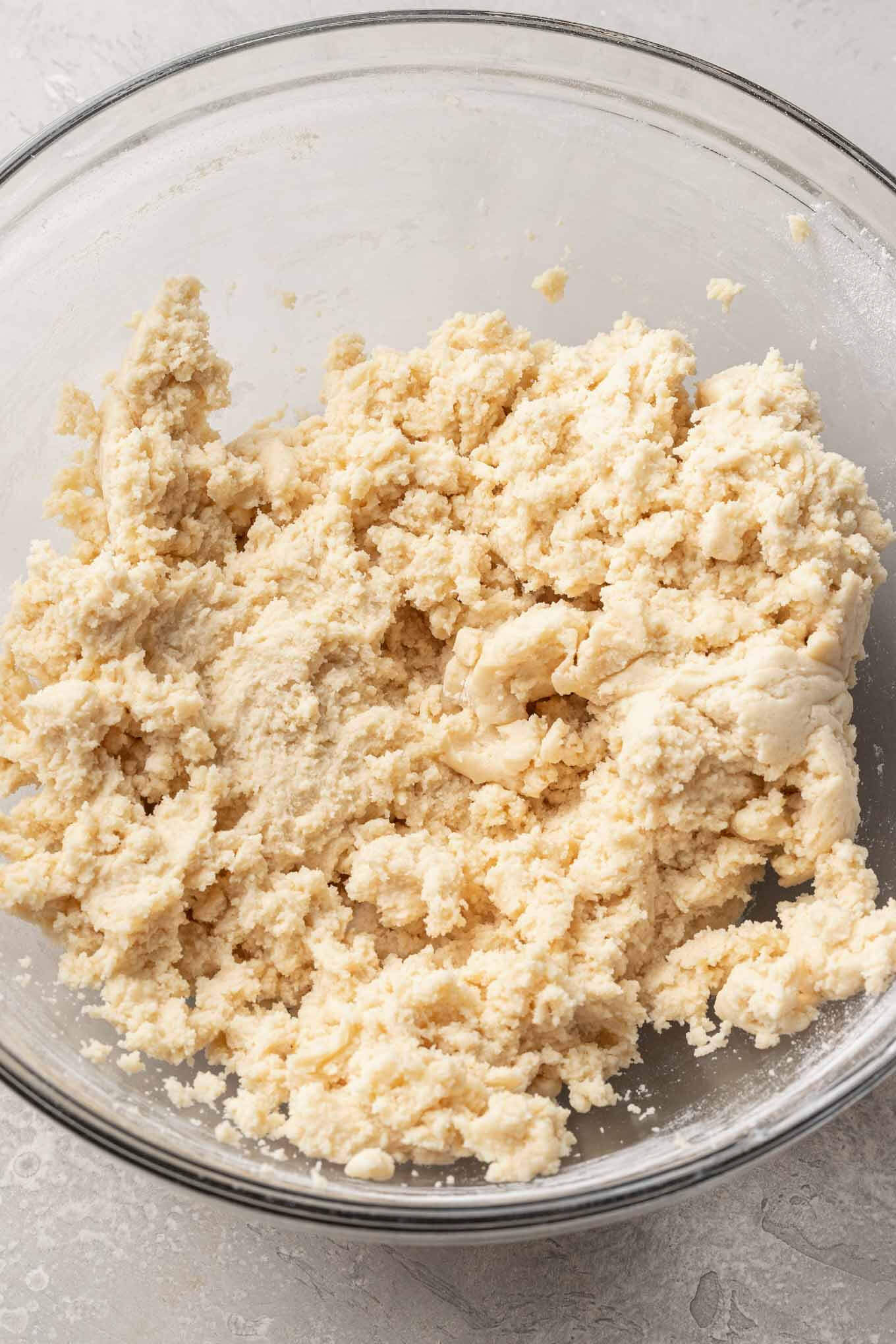 An overhead view of sugar cookie dough in a glass mixing bowl. 