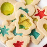 An overhead view of several stained glass cookies on a white plate.