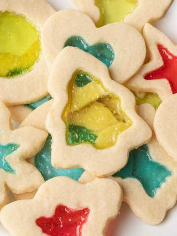 An overhead view of several stained glass cookies on a white plate.