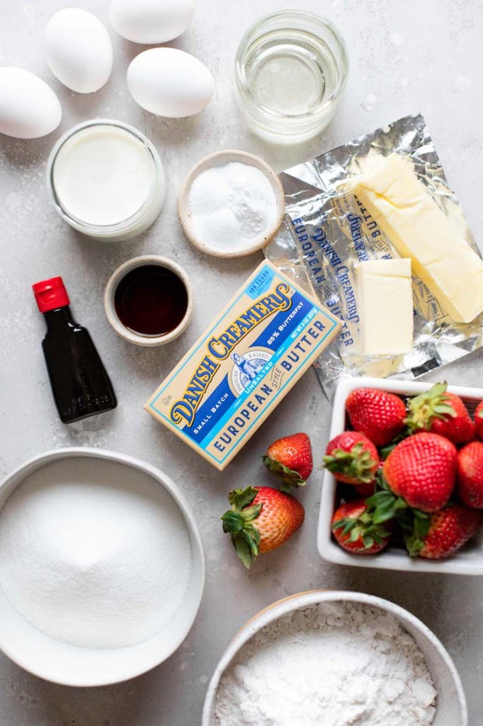 The ingredients needed to make a strawberry cake sitting on top of a gray surface.