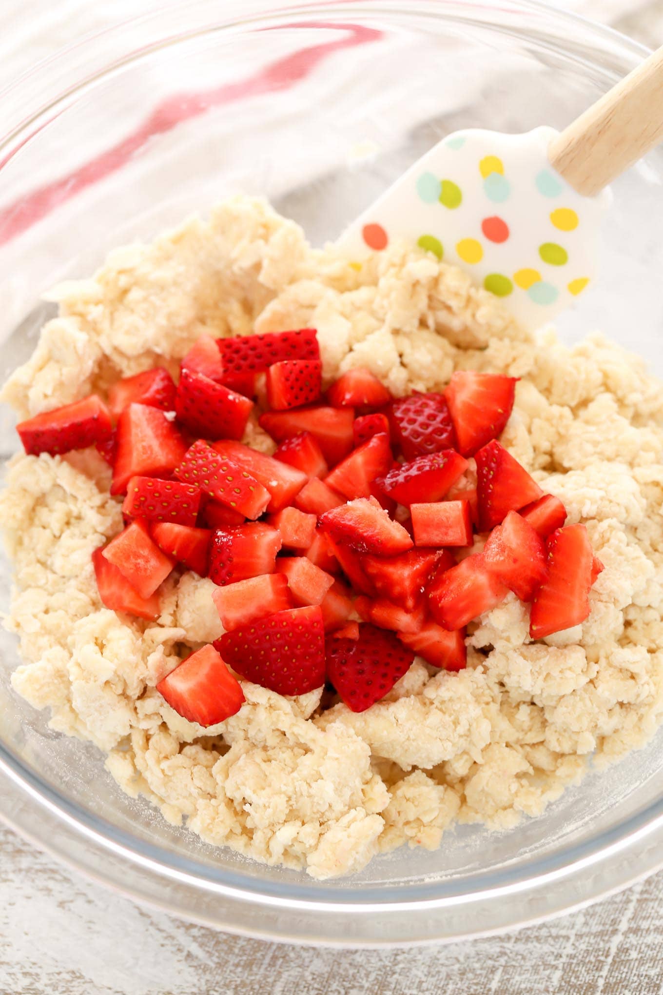 Chopped strawberries on top of scone dough in a glass bowl. 