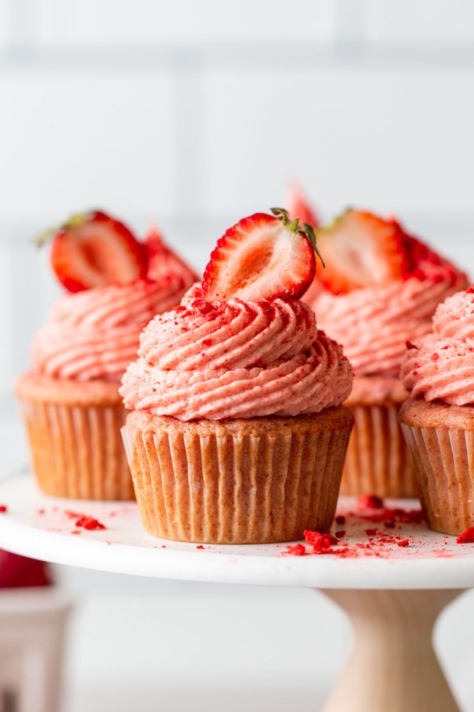 A side view of homemade strawberry cupcakes on a cake stand. 