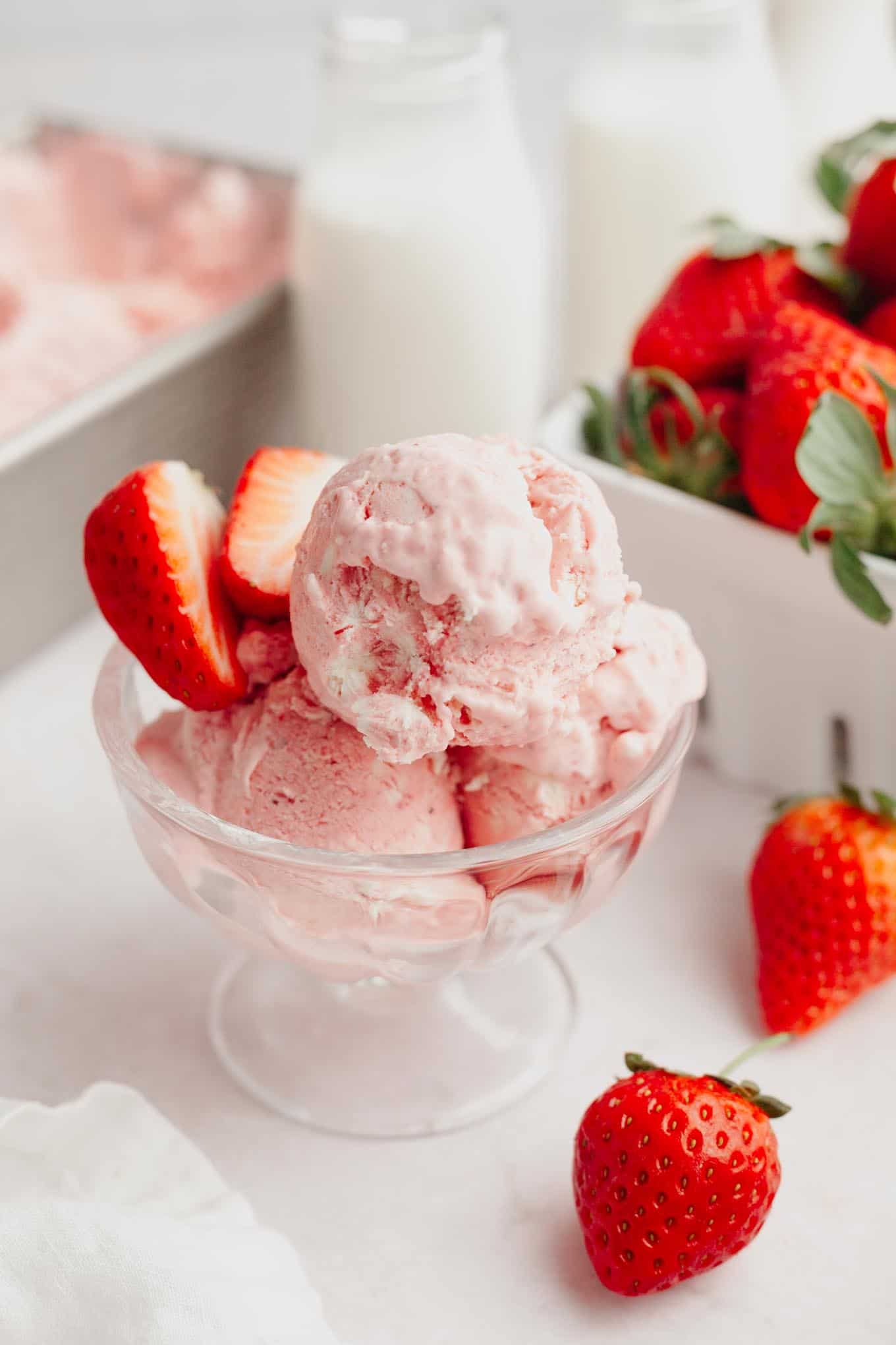 Three scoops of no churn strawberry ice cream in an ice cream dish. 