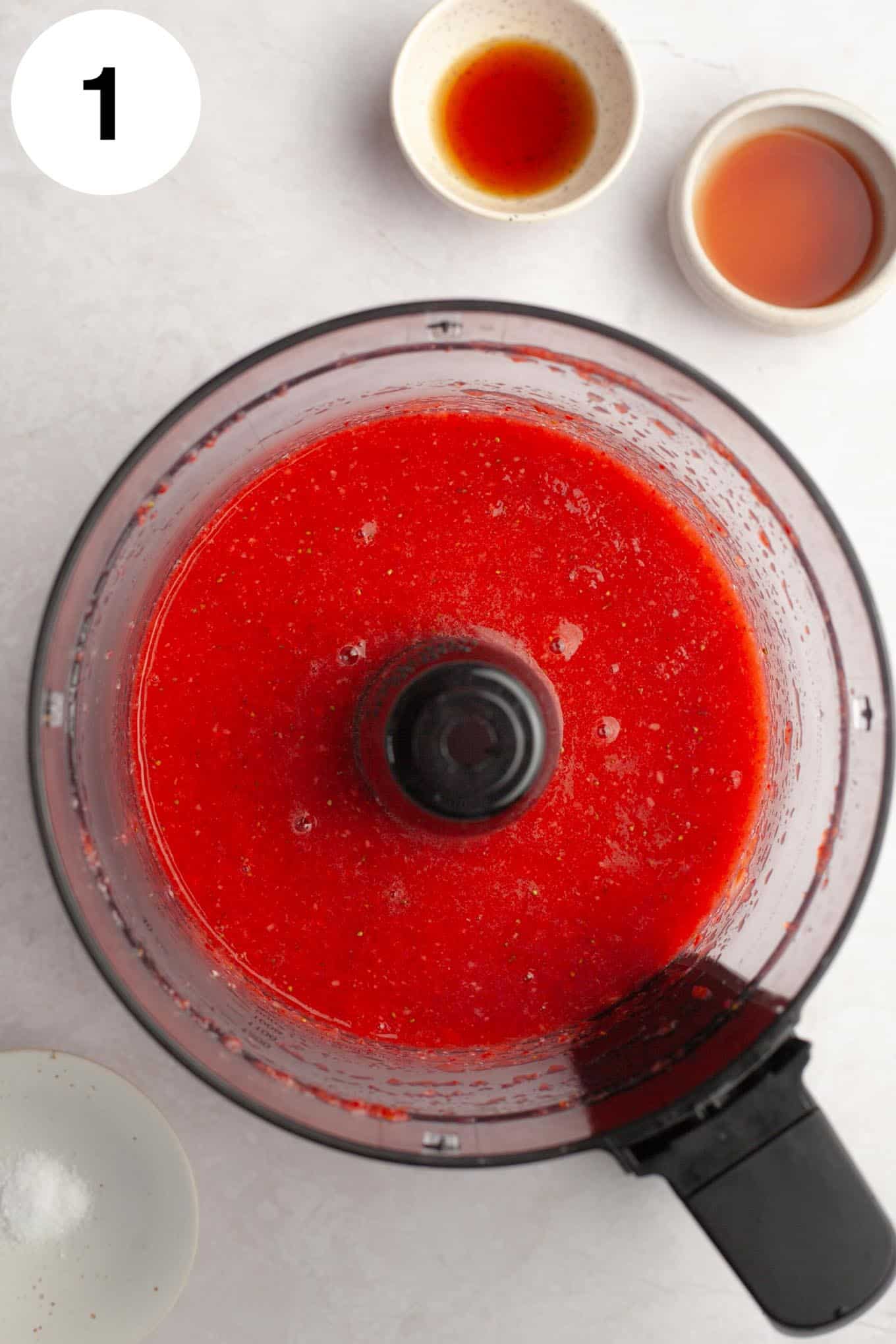 An overhead view of fresh strawberry puree in a food processor. 