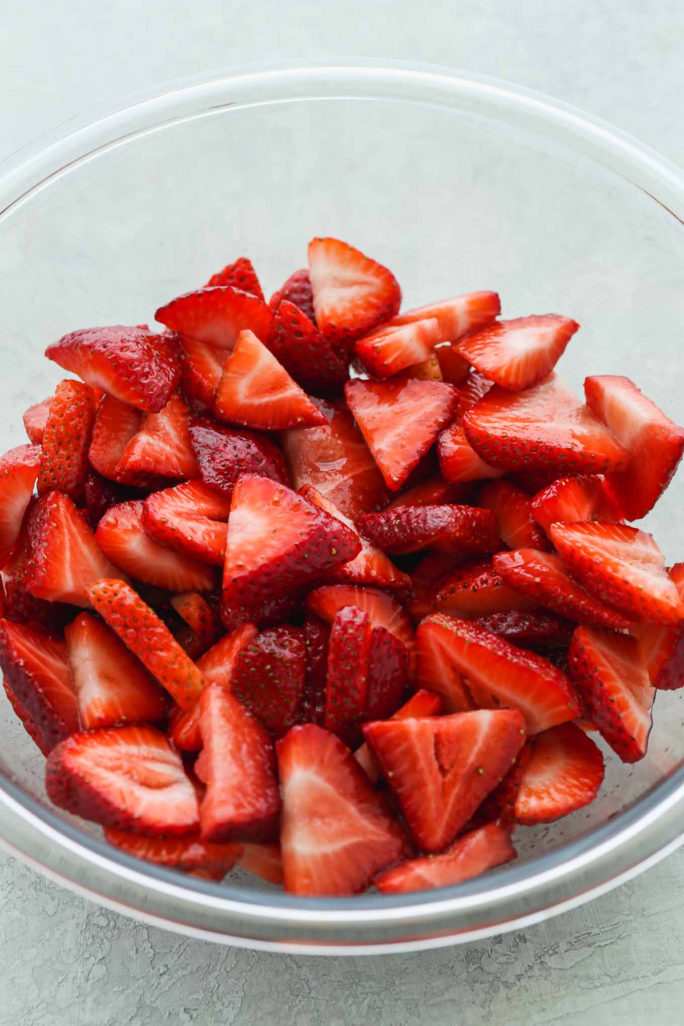 A glass bowl filled with freshly sliced strawberries.