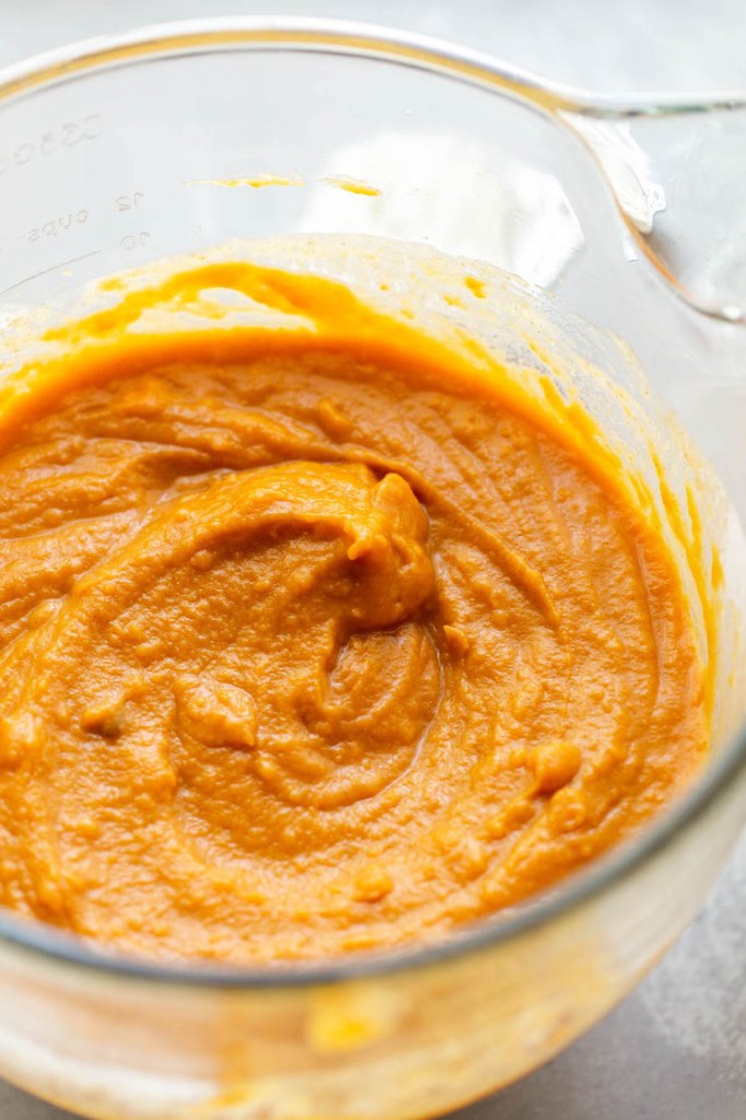 A glass mixing bowl holding mashed sweet potatoes. 