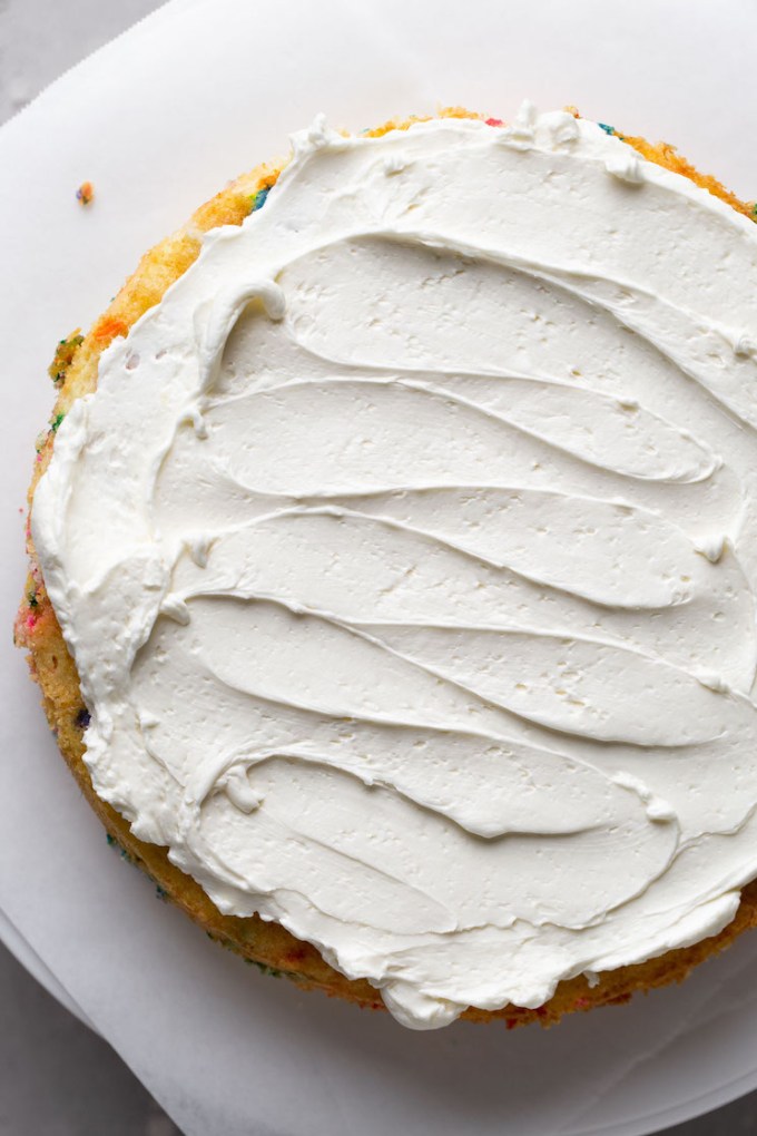 Overhead view of a cake layer topped with frosting.