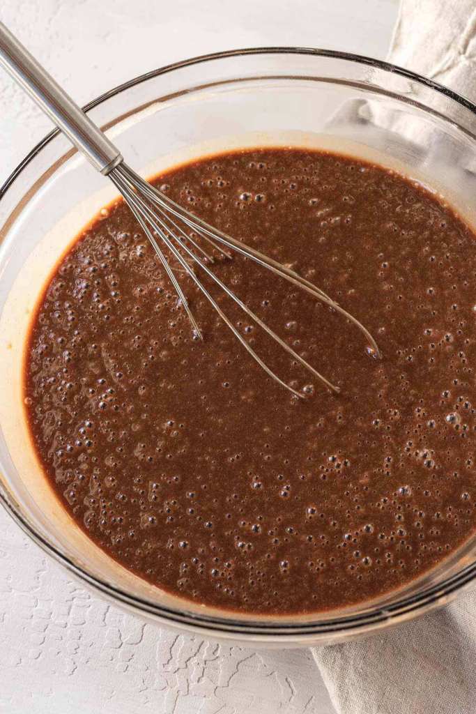 Texas sheet cake batter whisked together in a glass mixing bowl.