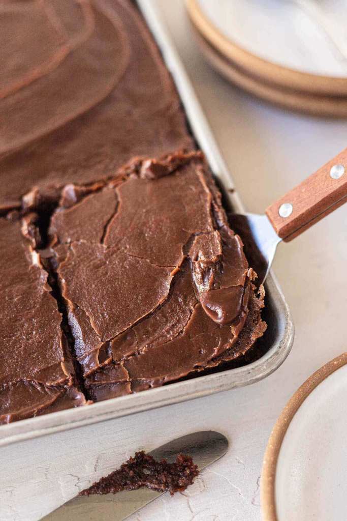 A slice of Texas sheet cake being removed from the pan. 