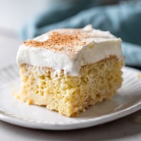 A slice of tres leches cake on a white plate.