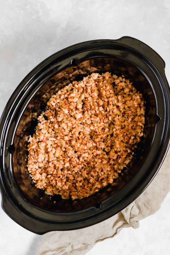 A crockpot filled with cooked ground turkey and onions.