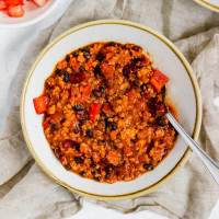 A bowl of turkey chili with a spoon resting in it.