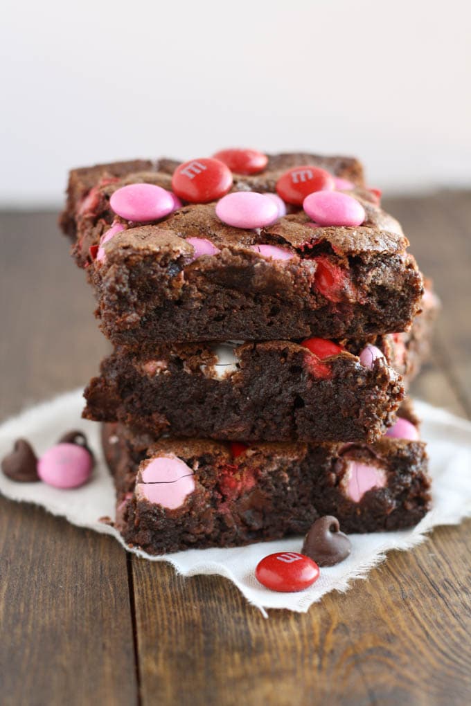 A stack of three chocolate chip M&M's brownies on a square of fabric. 