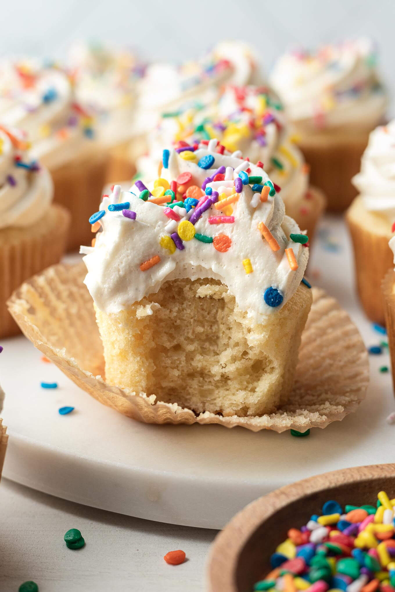 A side view of a cupcake with a bite missing and the cupcake liner pulled down. 