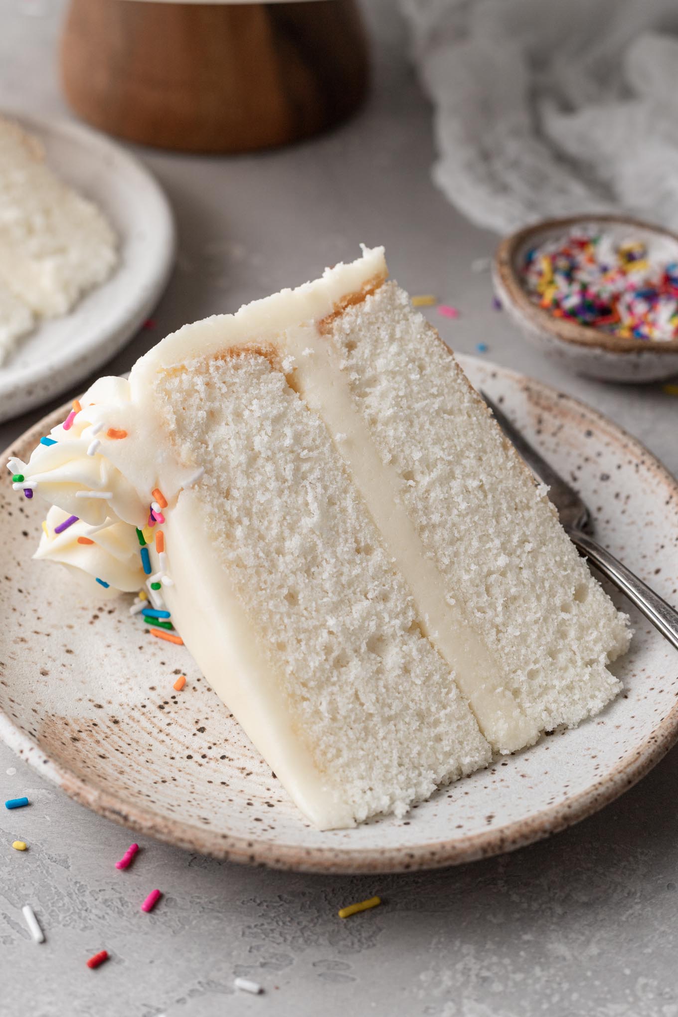 A slice of white cake on a dessert plate. 