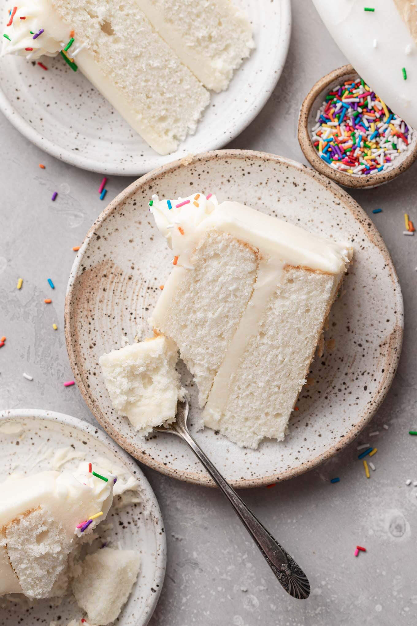 An overhead view of three white cake slices on dessert plates. 