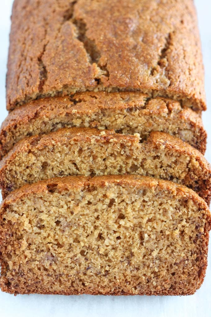 A loaf of whole wheat banana bread. The front section has been cut into three slices. 