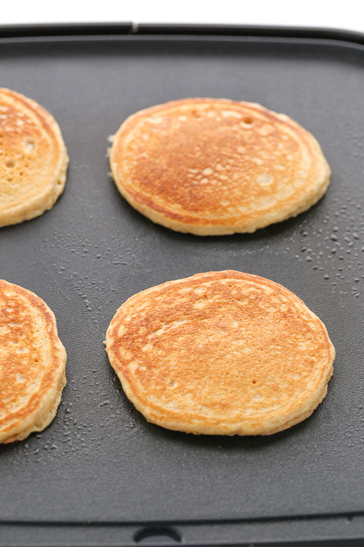 A black grilled topped with fully cooked whole wheat pancakes.