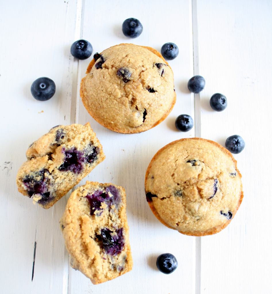 Overhead view of three healthy blueberry muffins. One muffin has been torn in half.