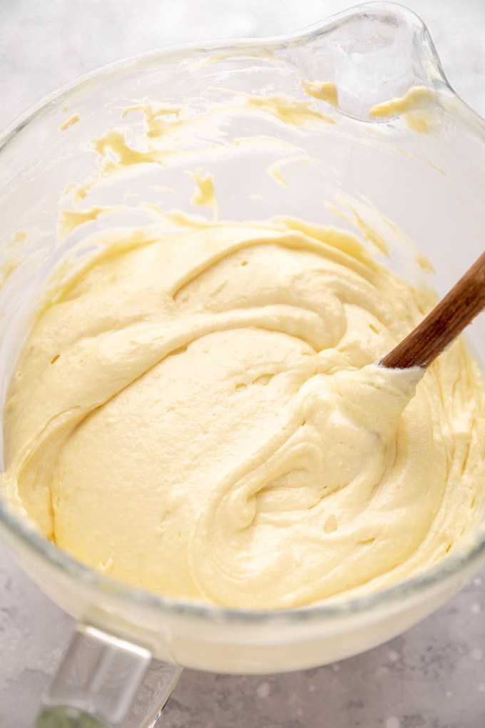 Yellow cake batter with egg whites folded into it in a glass mixing bowl.